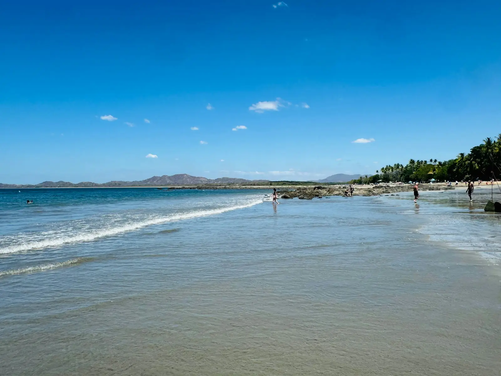 Tamarindo beach with Pacific waves and green hills in the distance